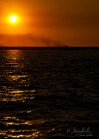 Sun set in a smoky sky as the Navy patrol Darwins coast