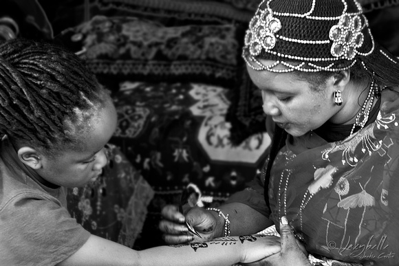 110626 Sudanese woman paints a childs arm with henna B&W